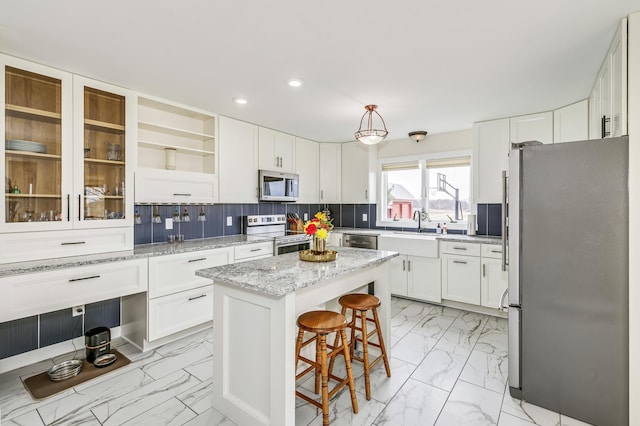 kitchen featuring marble finish floor, recessed lighting, white cabinets, a sink, and appliances with stainless steel finishes