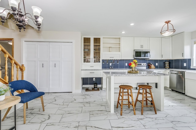 kitchen with recessed lighting, marble finish floor, appliances with stainless steel finishes, and a breakfast bar