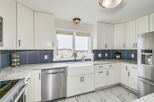 kitchen with marble finish floor, white cabinetry, a sink, appliances with stainless steel finishes, and backsplash
