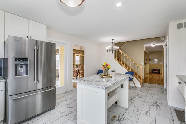 kitchen featuring visible vents, white cabinets, high end fridge, and marble finish floor