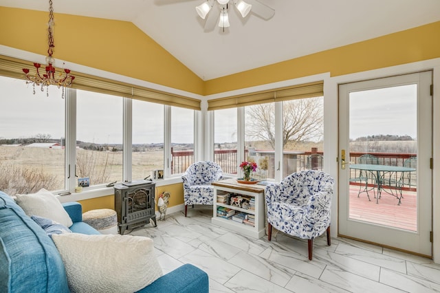 sunroom with plenty of natural light, a wood stove, lofted ceiling, and marble finish floor