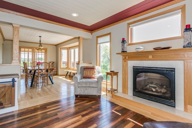 living room featuring a high end fireplace, hardwood / wood-style flooring, wooden ceiling, ornamental molding, and ornate columns