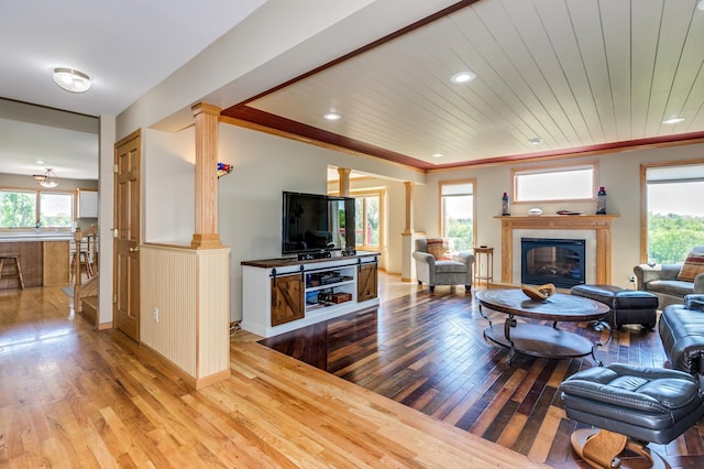 living room featuring recessed lighting, decorative columns, a glass covered fireplace, and hardwood / wood-style floors