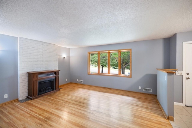 7872 142nd St W, Apple Valley, MN 55124 - unfurnished living room featuring a textured ceiling, a fireplace, and wood finished floors