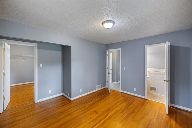 7872 142nd St W, Apple Valley, MN 55124 - unfurnished bedroom featuring a textured ceiling, wood finished floors, a closet, ensuite bath, and a spacious closet