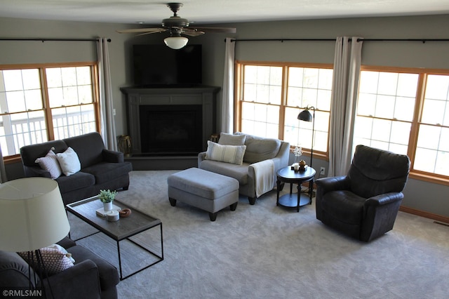 carpeted living room with visible vents, a ceiling fan, and a fireplace with raised hearth