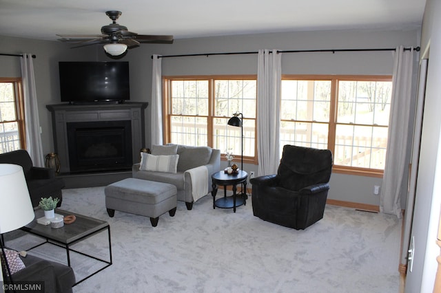 living area featuring a fireplace, ceiling fan, and carpet