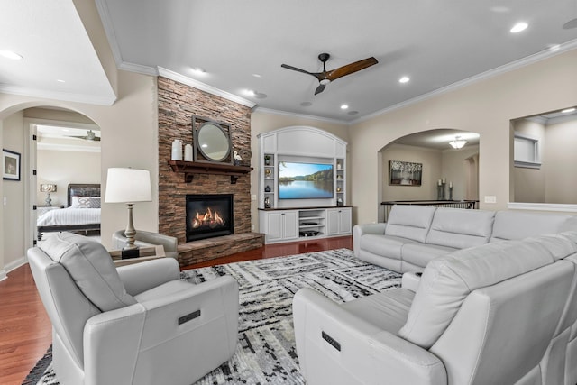 5435 Yellowstone Trl, Minnetrista, MN 55331 - living room featuring a ceiling fan, arched walkways, wood finished floors, crown molding, and a stone fireplace