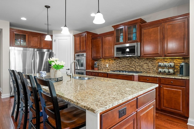 5435 Yellowstone Trl, Minnetrista, MN 55331 - kitchen with stainless steel appliances, a sink, dark wood-style floors, decorative backsplash, and a kitchen island with sink