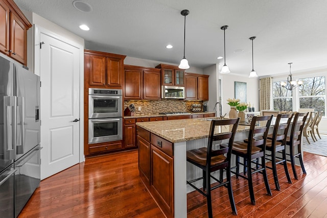 5435 Yellowstone Trl, Minnetrista, MN 55331 - kitchen with stainless steel appliances, dark wood-type flooring, a sink, tasteful backsplash, and light stone counters