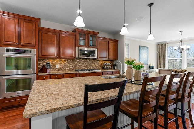 5435 Yellowstone Trl, Minnetrista, MN 55331 - kitchen featuring appliances with stainless steel finishes, a sink, dark wood-style floors, decorative backsplash, and pendant lighting