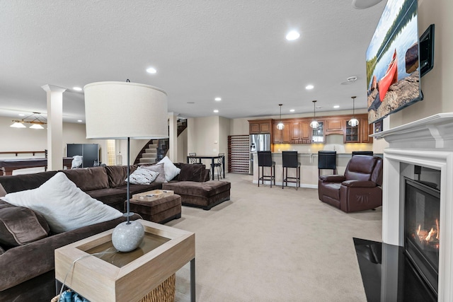 5435 Yellowstone Trl, Minnetrista, MN 55331 - living area with stairs, a glass covered fireplace, light colored carpet, recessed lighting, and a textured ceiling
