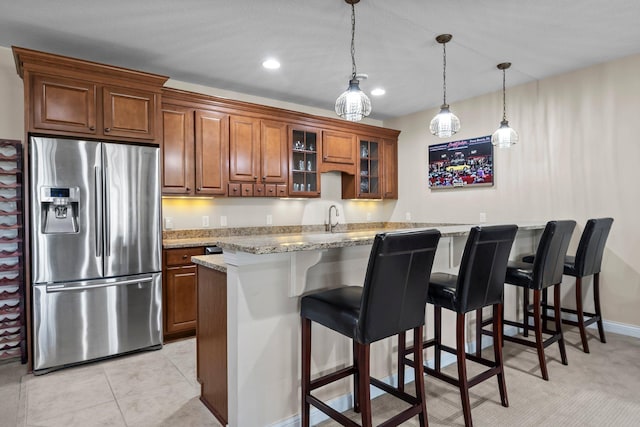 5435 Yellowstone Trl, Minnetrista, MN 55331 - kitchen with stainless steel fridge with ice dispenser, brown cabinetry, a kitchen bar, glass insert cabinets, and pendant lighting