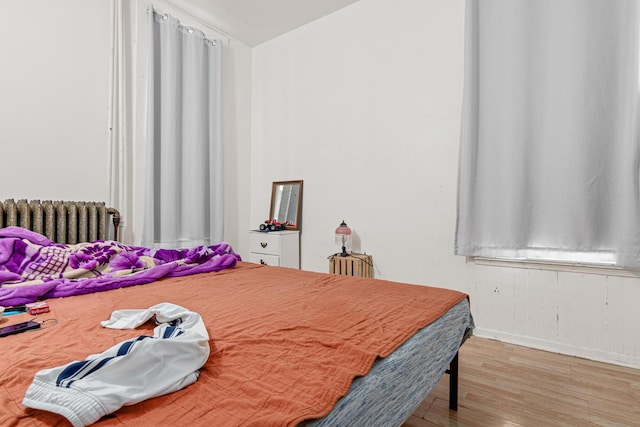 bedroom featuring baseboards, radiator, and wood finished floors