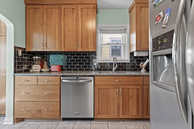 kitchen with a sink, decorative backsplash, brown cabinetry, and stainless steel appliances