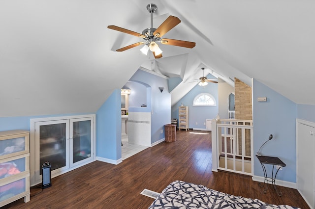 additional living space with wood finished floors, lofted ceiling, baseboards, ceiling fan, and arched walkways
