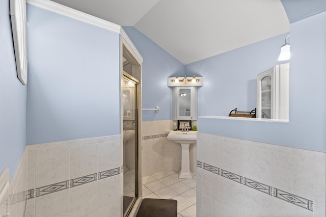 full bathroom with lofted ceiling, tile walls, tile patterned floors, a wainscoted wall, and a shower stall