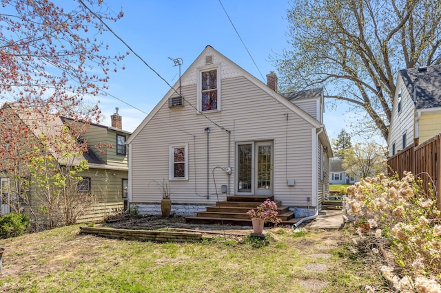 back of property featuring entry steps, a chimney, and a lawn