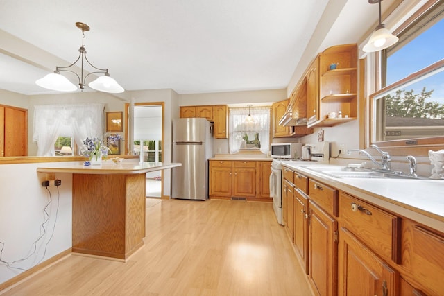 517 2nd St, Waconia, MN 55387 - kitchen featuring white appliances, light countertops, light wood-type flooring, decorative light fixtures, and brown cabinetry