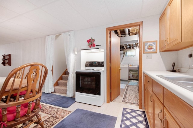 517 2nd St, Waconia, MN 55387 - kitchen with electric range, washer / dryer, under cabinet range hood, light countertops, and light brown cabinets