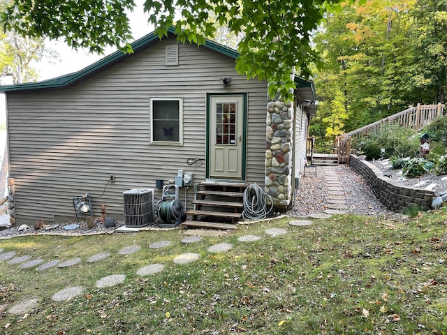 rear view of house with cooling unit, a yard, and entry steps