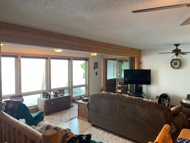 living area featuring a ceiling fan, a textured ceiling, and light wood-type flooring