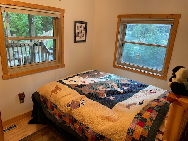 bedroom with visible vents, baseboards, and wood finished floors