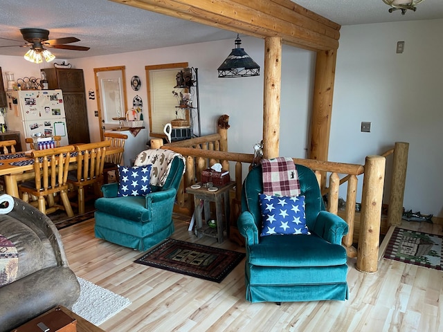living area featuring a textured ceiling, a ceiling fan, and wood finished floors