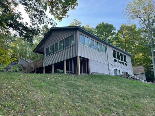 back of house featuring a lawn, stone siding, and stairway