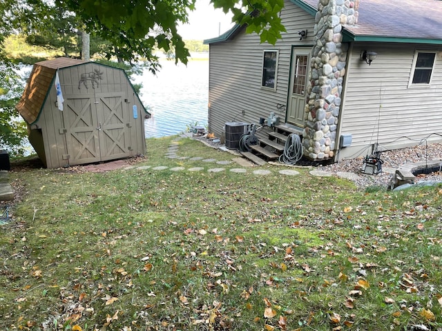 view of side of home featuring a lawn, an outbuilding, cooling unit, a storage unit, and entry steps