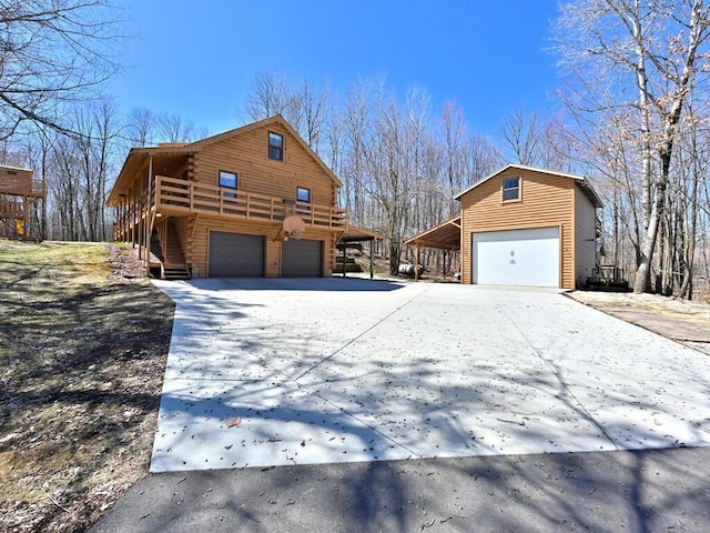 20703 Aspen Dr, Grand Rapids, MN 55744 - view of home's exterior featuring a deck, stairway, log exterior, concrete driveway, and an attached garage