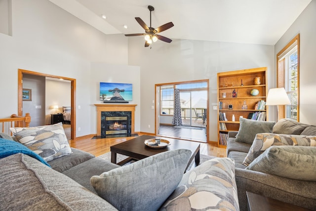 living area with ceiling fan, plenty of natural light, light wood-style flooring, and a high end fireplace