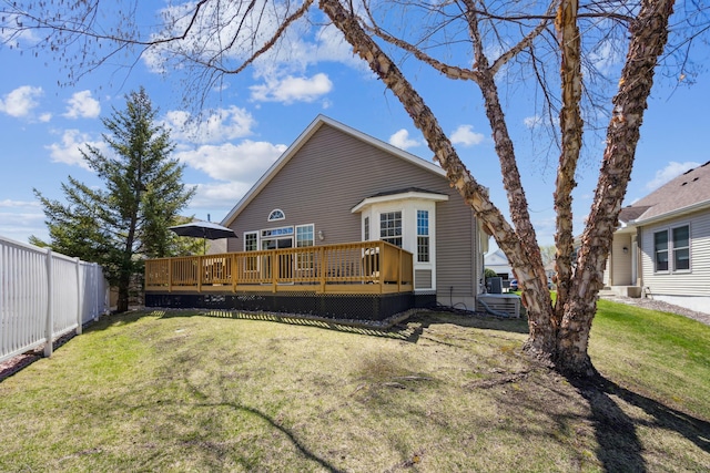 rear view of property with fence, a lawn, and a deck