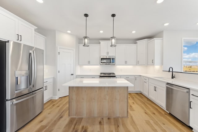 kitchen featuring appliances with stainless steel finishes, a sink, light wood-style flooring, light countertops, and recessed lighting