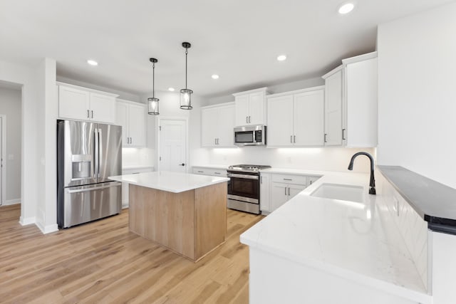 kitchen featuring appliances with stainless steel finishes, a sink, light wood-type flooring, recessed lighting, and a kitchen island