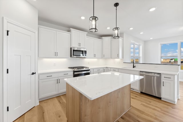 kitchen with stainless steel appliances, light wood-style floors, a peninsula, a sink, and recessed lighting