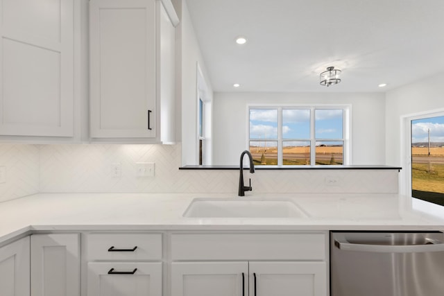 kitchen featuring dishwasher, a sink, decorative backsplash, white cabinets, and light countertops