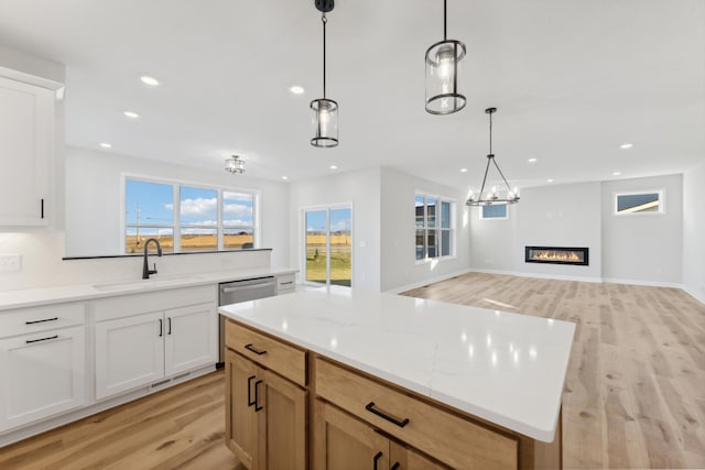 kitchen with a sink, light wood finished floors, open floor plan, recessed lighting, and decorative light fixtures