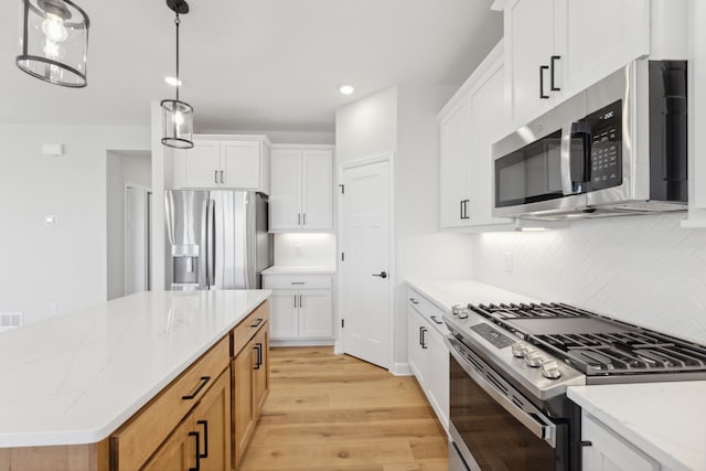 kitchen with appliances with stainless steel finishes, light wood-style flooring, tasteful backsplash, white cabinetry, and decorative light fixtures