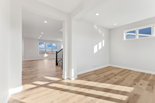 spare room featuring baseboards, light wood-type flooring, recessed lighting, and stairway
