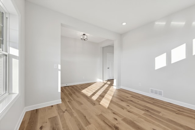 empty room with light wood finished floors, plenty of natural light, baseboards, and recessed lighting