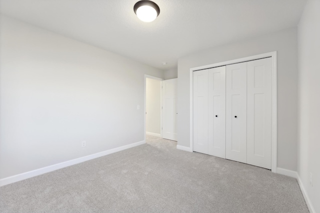 unfurnished bedroom featuring carpet, baseboards, and a closet