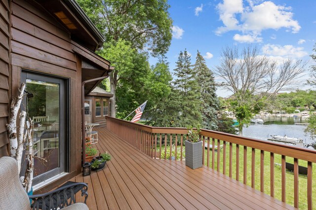 wooden terrace featuring a water view and a yard