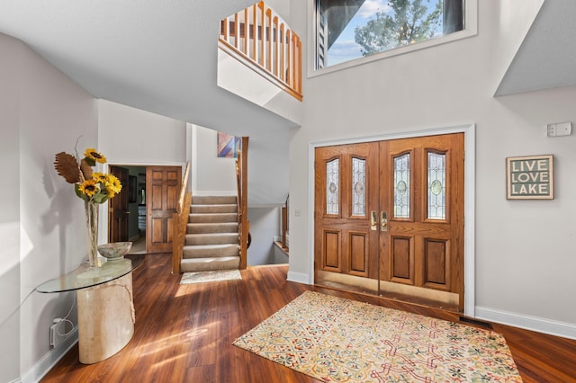 foyer entrance with stairway, wood finished floors, baseboards, and a high ceiling