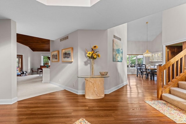 hallway featuring vaulted ceiling, stairs, baseboards, and wood finished floors