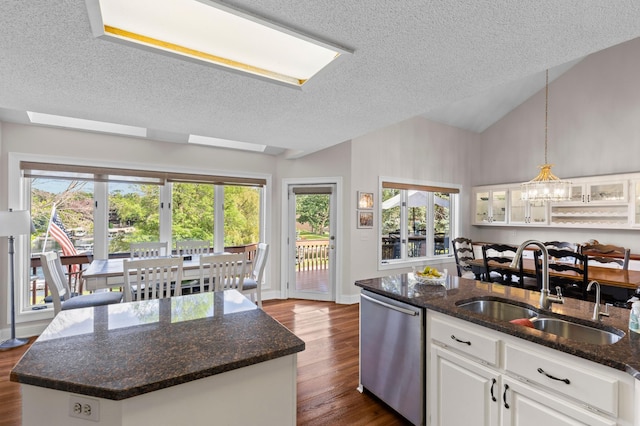 kitchen featuring stainless steel dishwasher, a textured ceiling, dark wood-type flooring, a sink, and white cabinetry