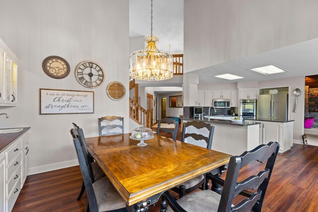 dining space with a high ceiling, dark wood-style floors, baseboards, a chandelier, and stairs