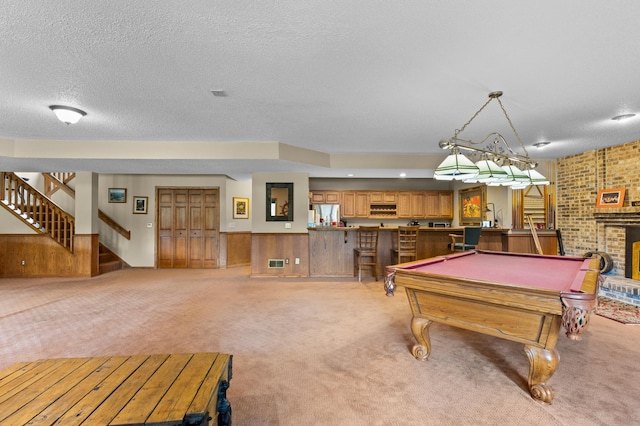 recreation room featuring light carpet, pool table, a textured ceiling, and a brick fireplace