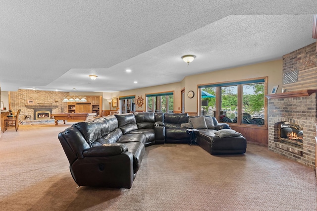living area with a brick fireplace, carpet, and a textured ceiling