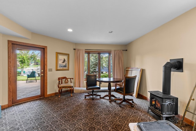 sitting room featuring baseboards, a wood stove, recessed lighting, and carpet